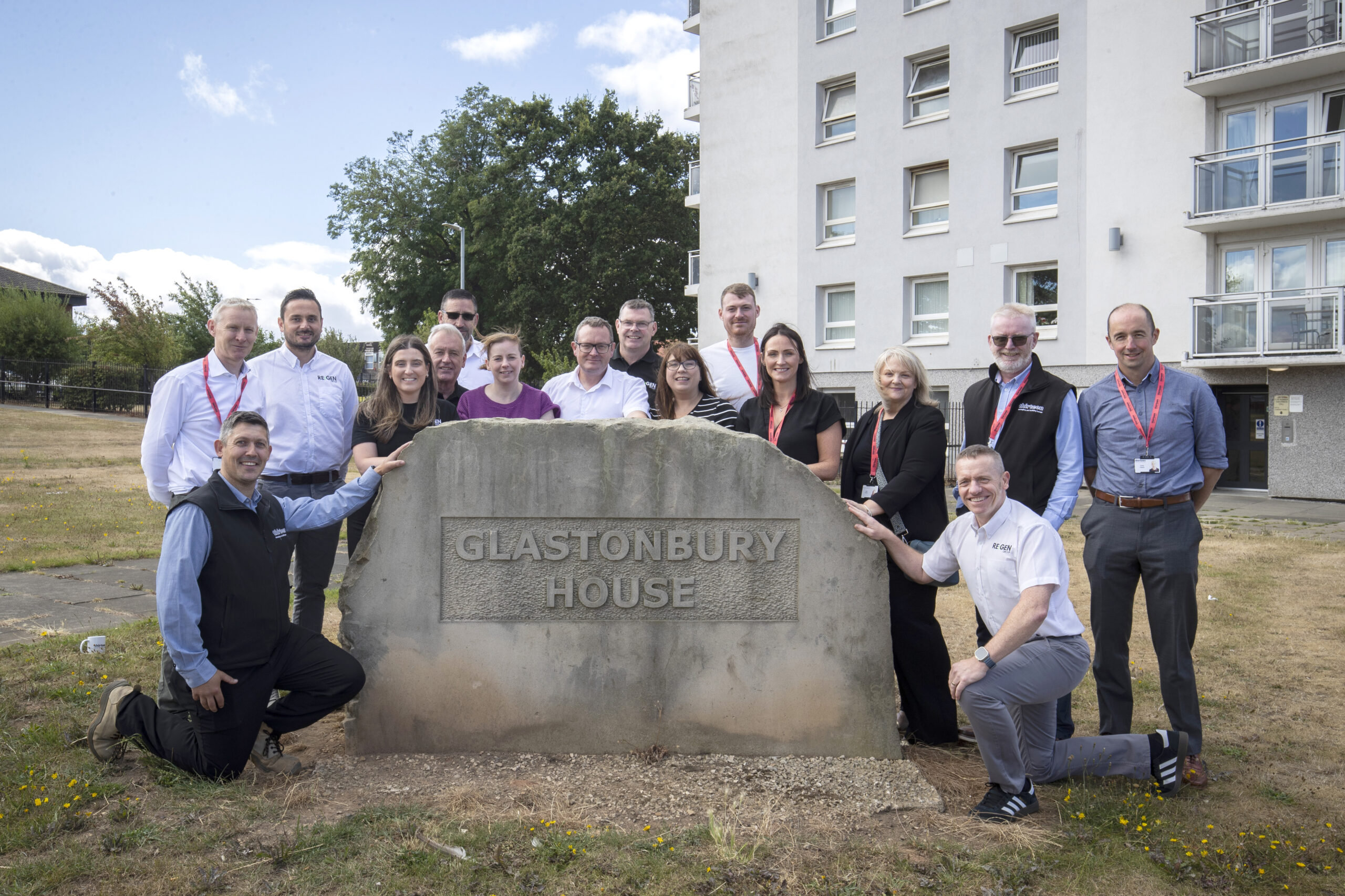Team members from Thirteen Housing and REGEN North East gather outside of tower block Glastonbury House to mark the completion of refurbishment works