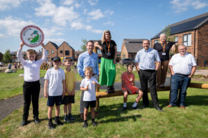 Team members from RE:GEN North East and Gentoo stand in the new play ground with local children to celebrate opening of new build housing development, Cricketers Hill
