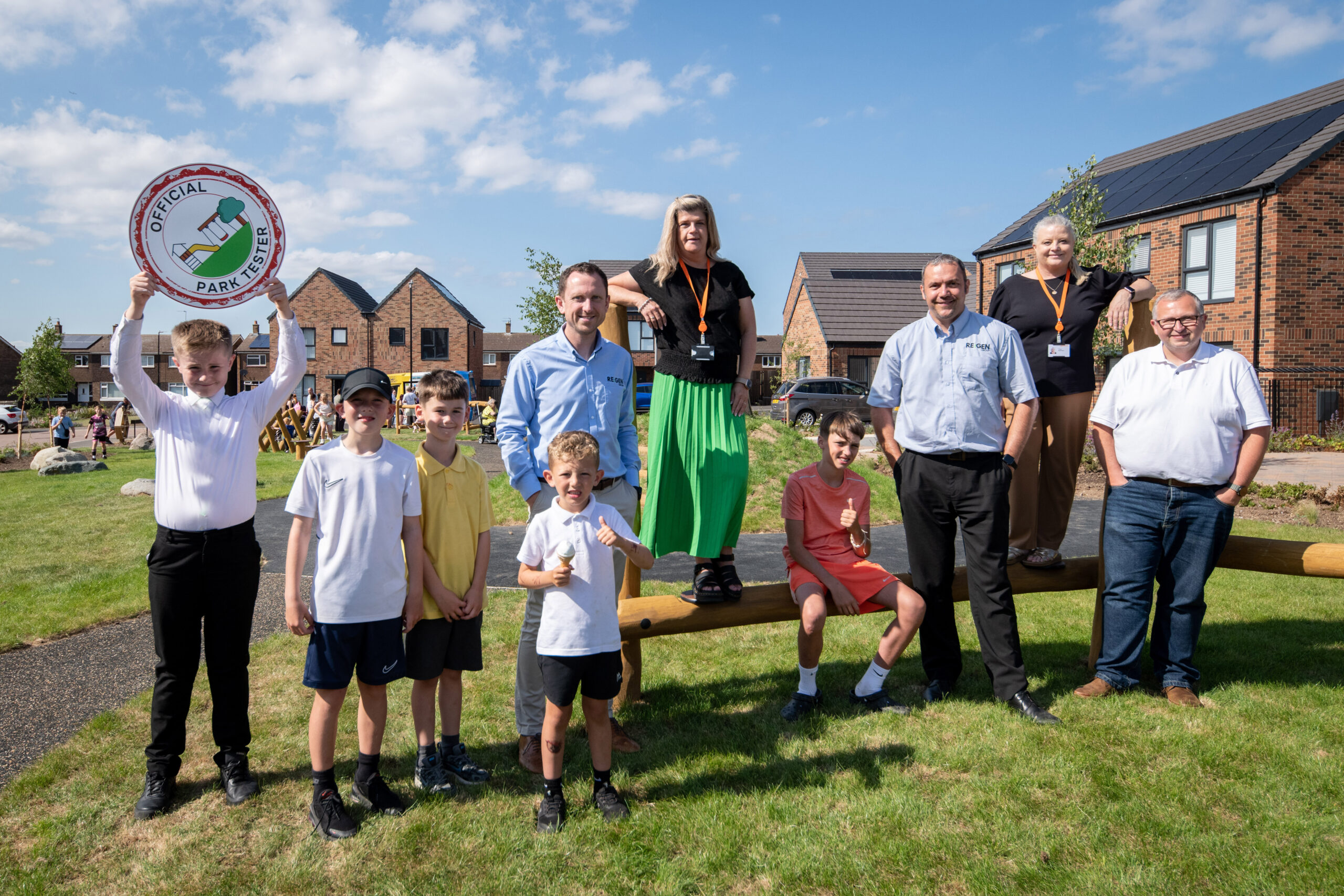 Team members from RE:GEN North East and Gentoo stand in the new play ground with local children to celebrate opening of new build housing development, Cricketers Hill